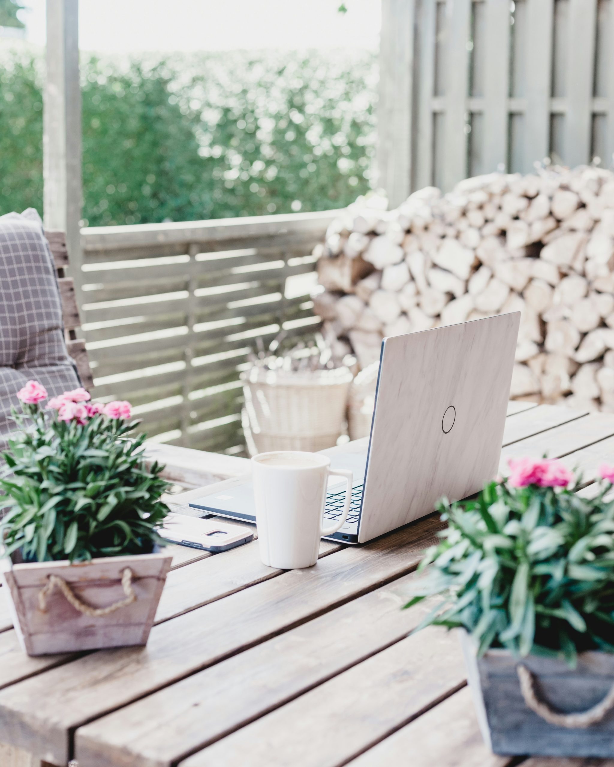 Image of a laptop sitting on a table outside with plants nearby